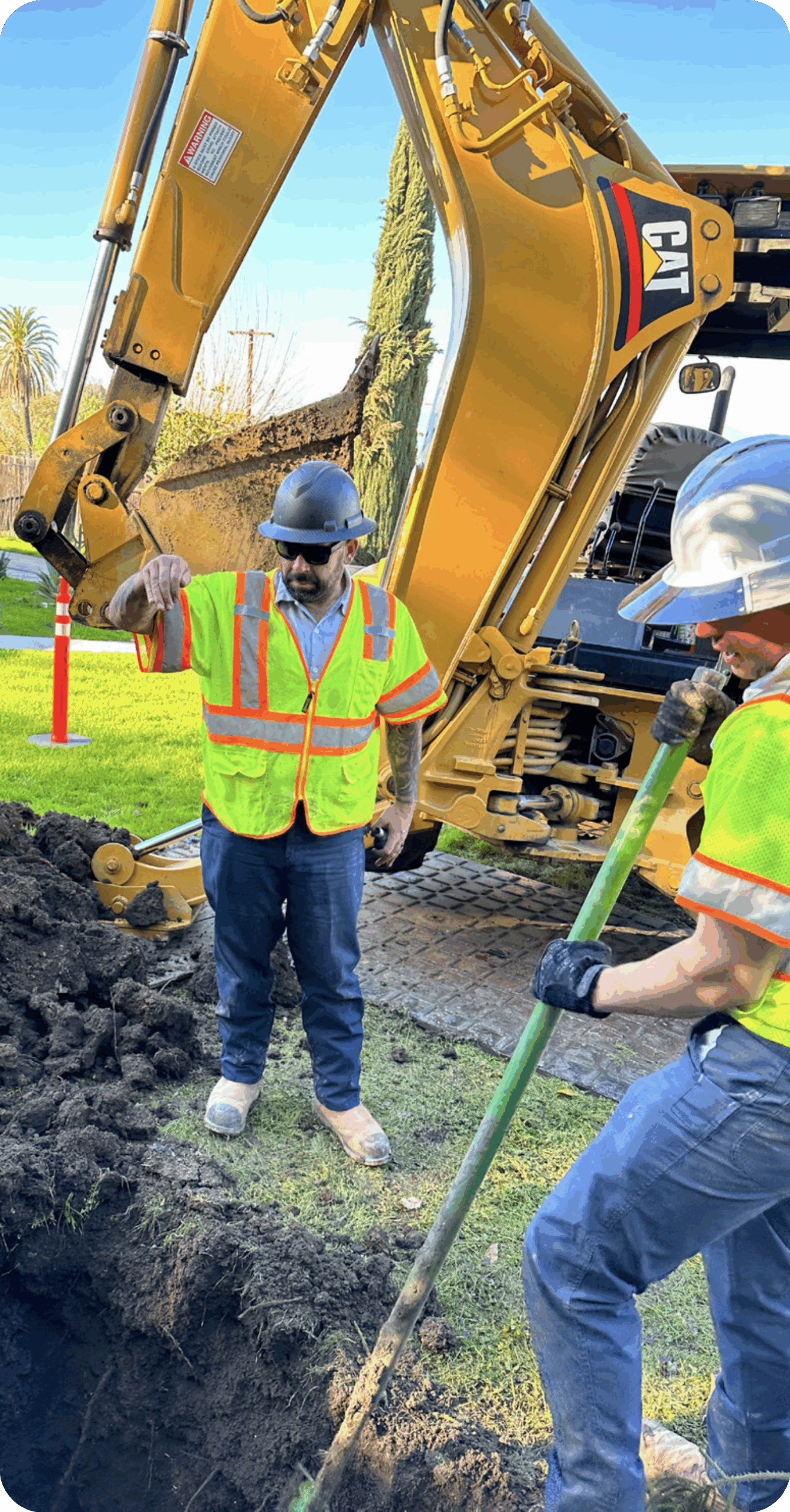 2 construction workers digging a hole in the ground